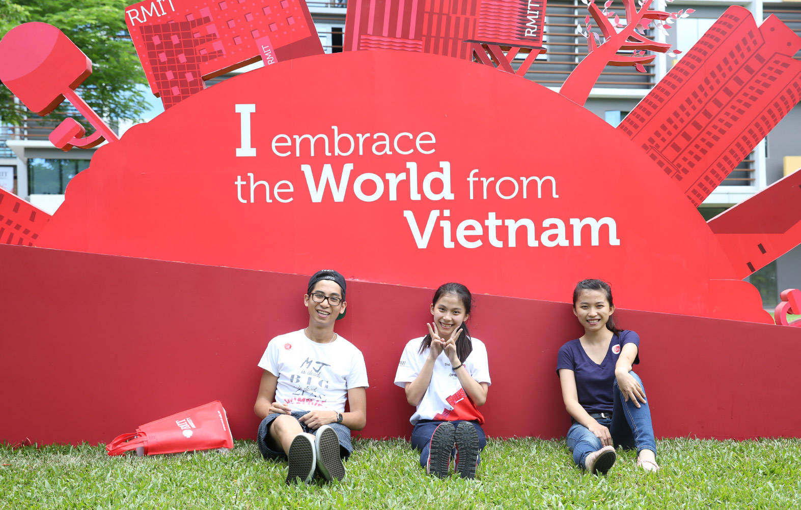 students sitting under a sign that reads I embrace the world from Vietnam