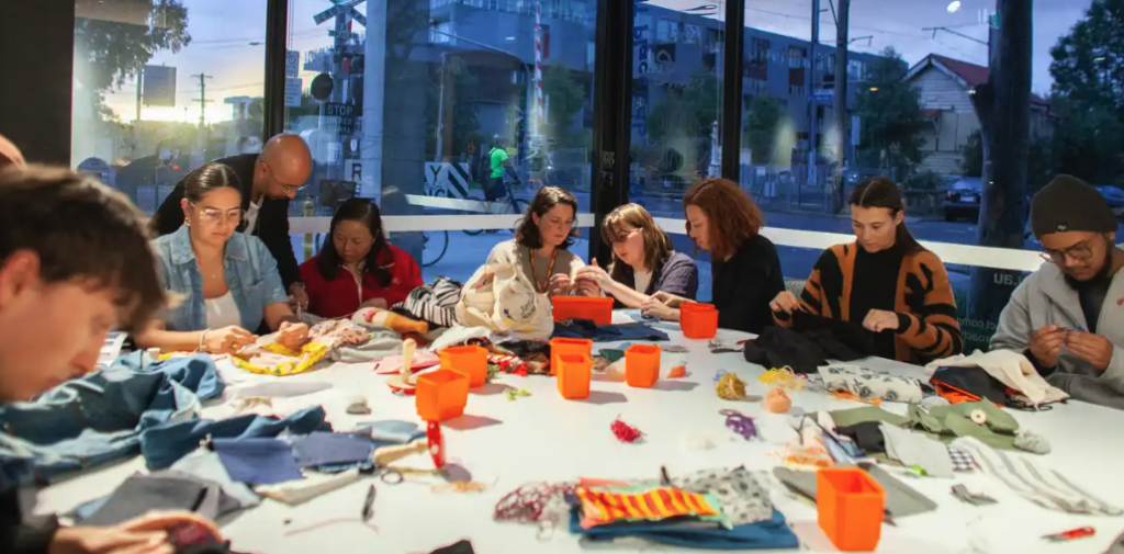People sitting at a table, taking part in a hand sewing workshop