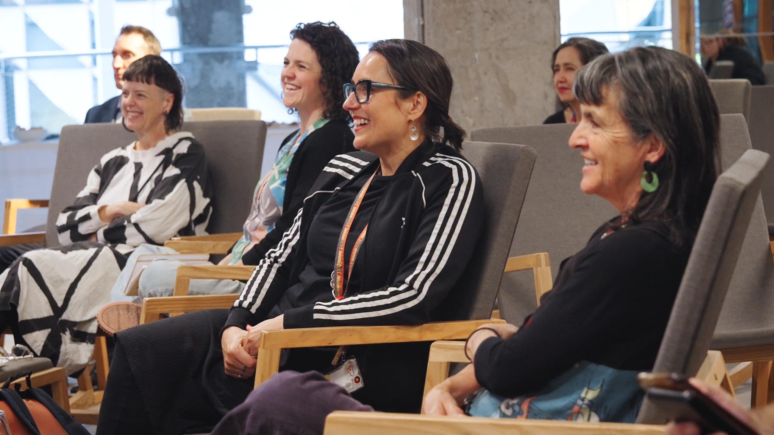 A group of people sitting a smiling looking in the same direction. 