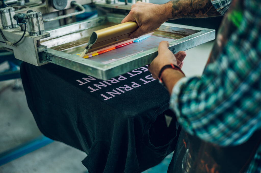 Worker screen printing on black t-shirt.
