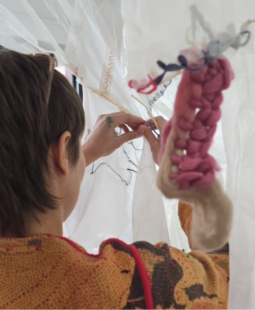 Mending a white curtain with different colour stitches.